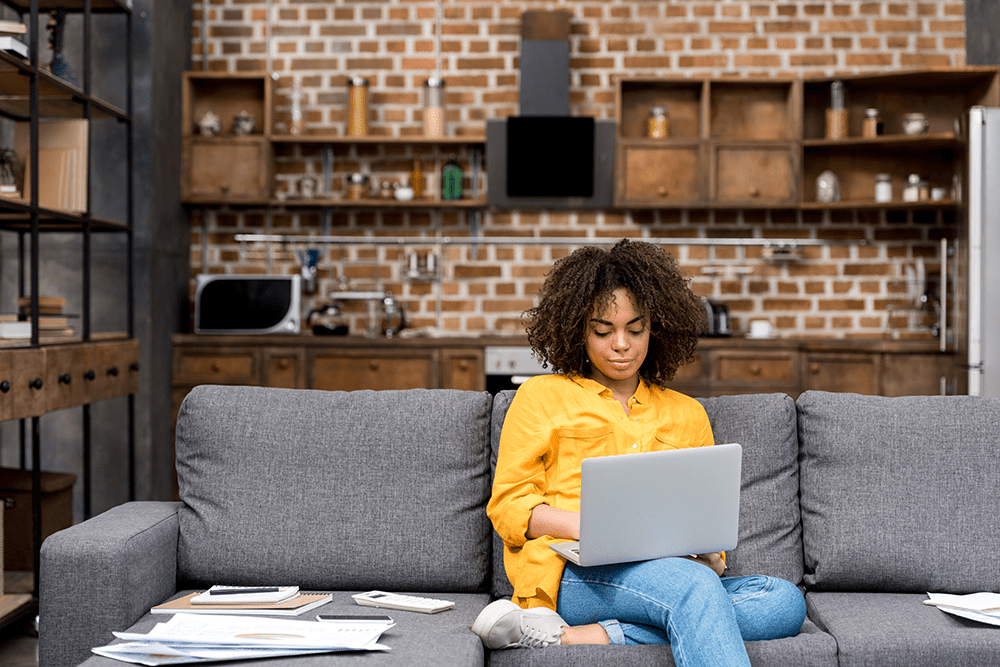 female working from home on a sofa with a laptop