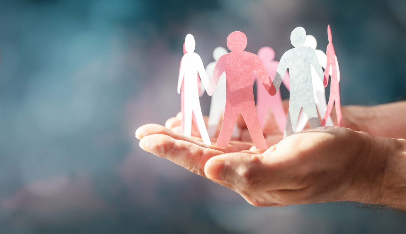 A circular chain of paper dolls being held in someone’s hands