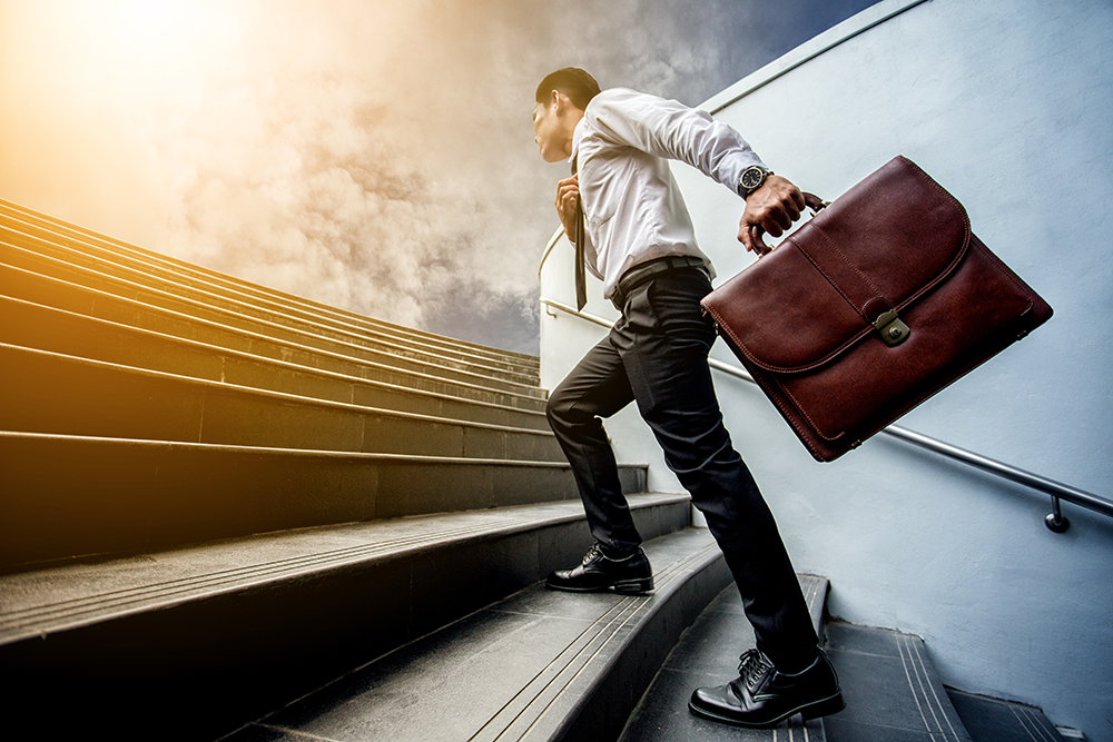 Benefits Planning in the New Normal | FlexGenius | Man walking upstairs with briefcase